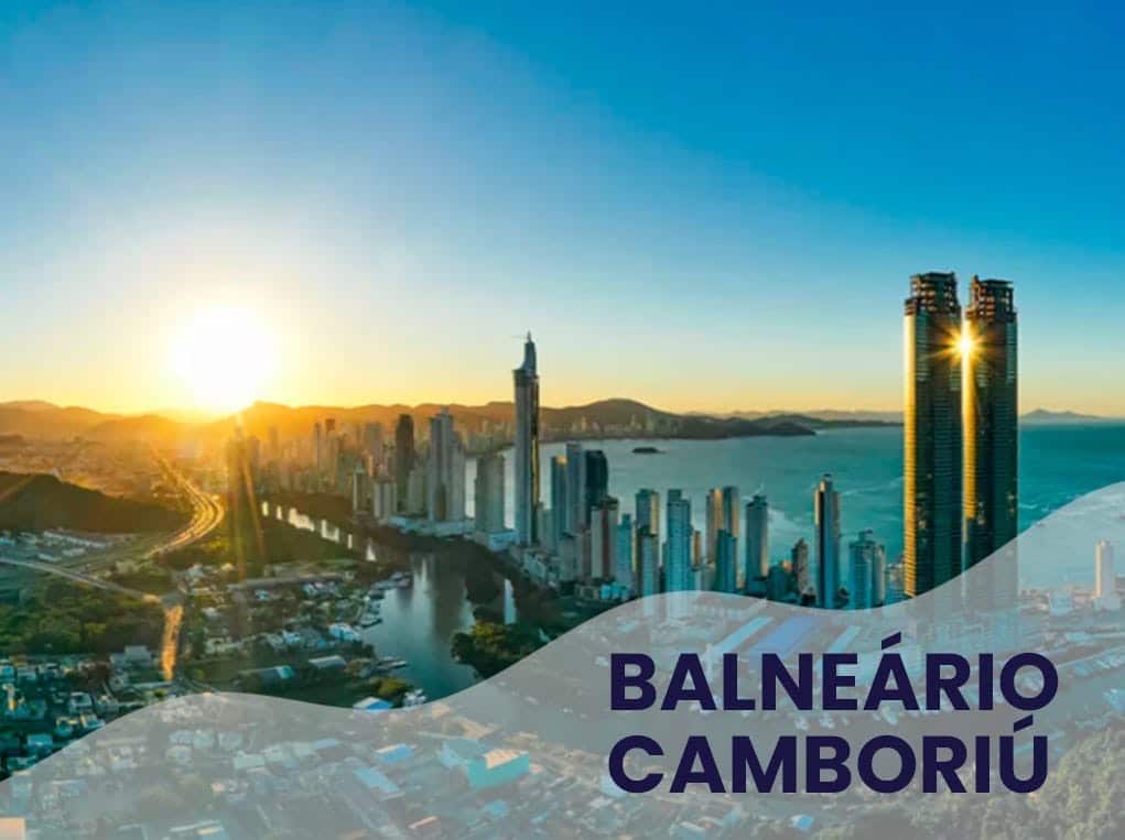 Vista panorâmica de Balneário Camboriú ao amanhecer. Arranha-céus e oceano sob céu azul.