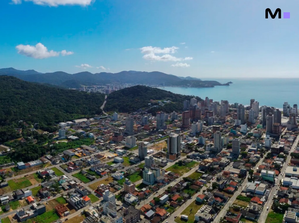 Vista aérea de Balneário Camboriú, com prédios altos e montanhas ao fundo. Grand View Residence.