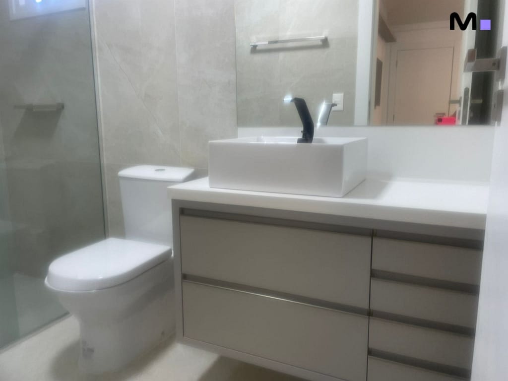 Banheiro moderno com pia branca, vaso sanitário e espelho. Condomínio House Haras.