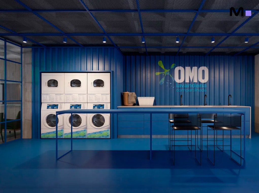 Lavanderia OMO compartilhada em Down Town by Housi. Máquinas de lavar e bancada azul.