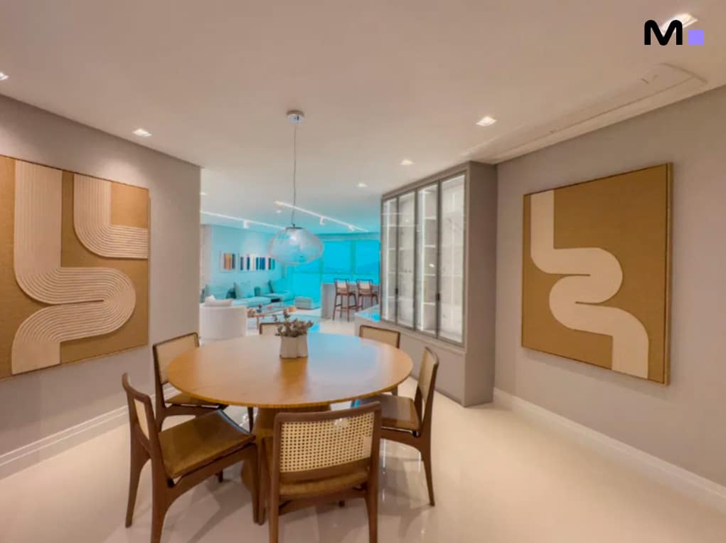 Sala de jantar moderna com mesa redonda e obras de arte nas paredes no Infinity Coast Residence.