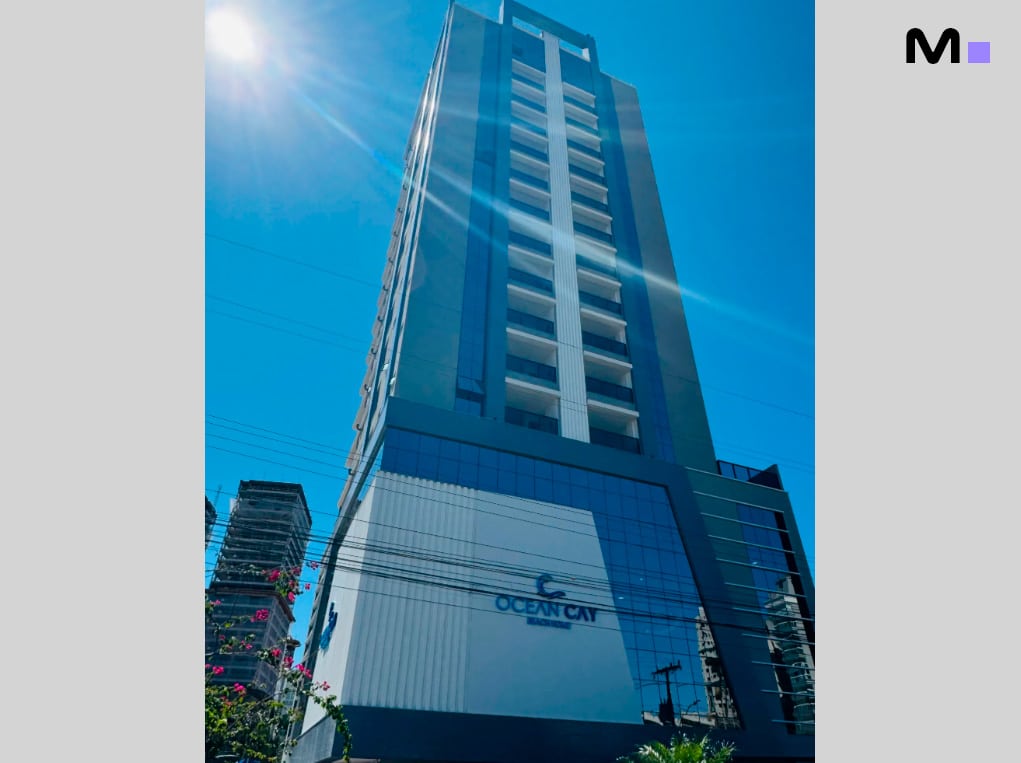 Edifício Ocean Cay em dia ensolarado. Arquitetura moderna com detalhes em vidro e linhas verticais.
