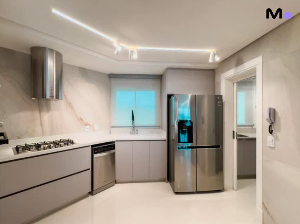 Cozinha moderna com geladeira inox e iluminação elegante. Infinity Coast Residence.