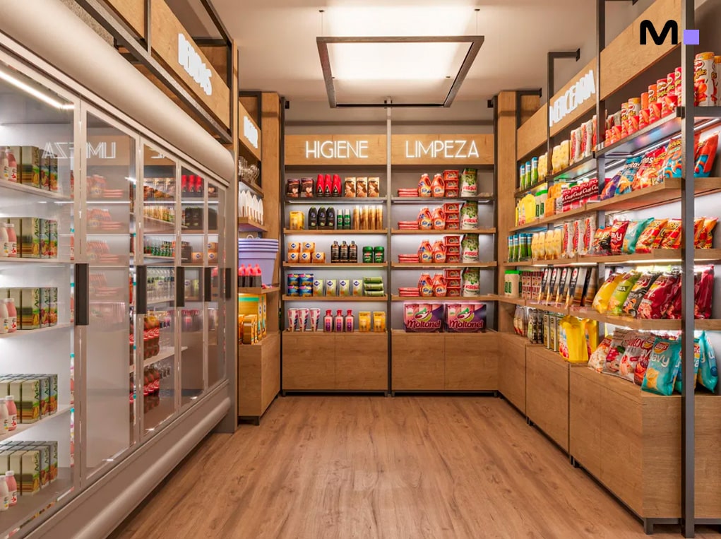 Interior de loja de conveniência bem iluminada com corredores organizados e produtos variados.