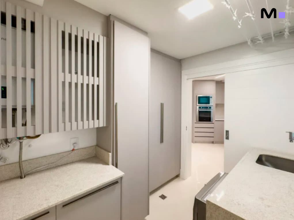 Lavanderia moderna com armários cinza claro e bancada de granito. Design clean e funcional.