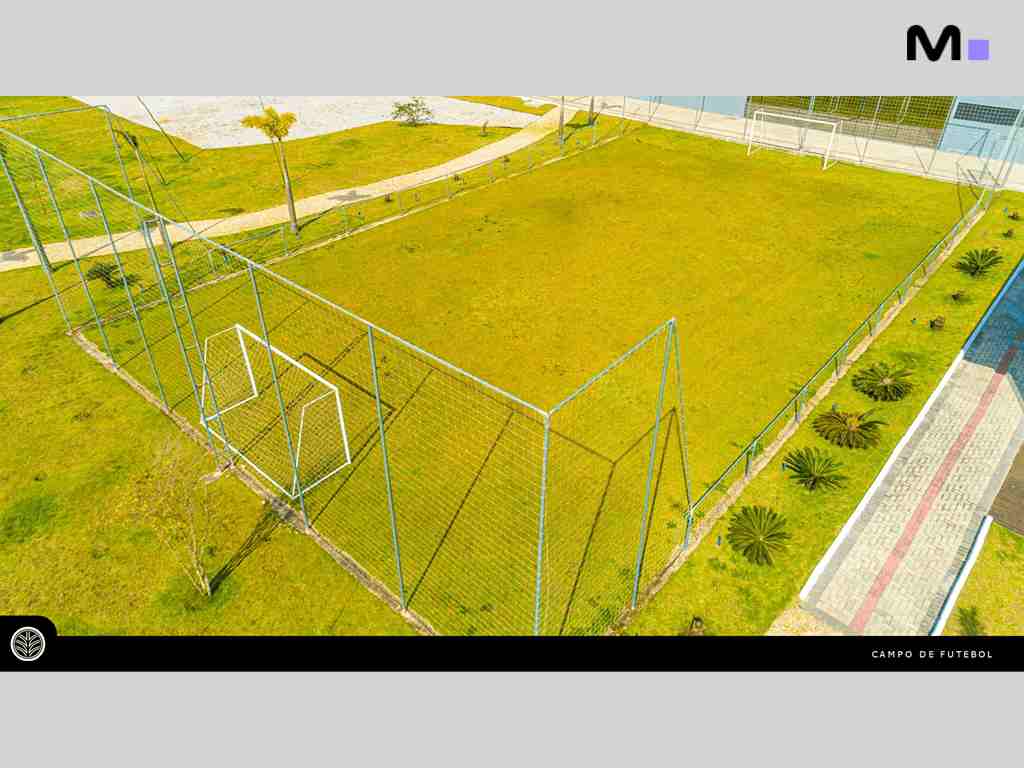 Campo de futebol no ABC Business Park com gramado verde e cercado por tela.