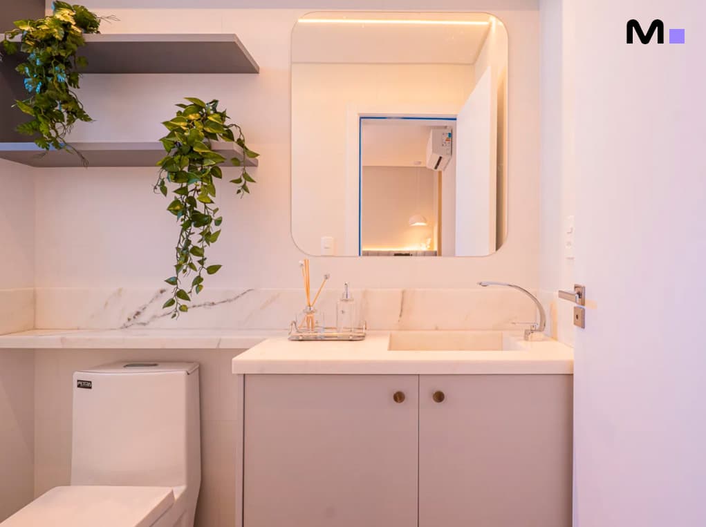 Banheiro moderno do Edifício Leblon Residence com pia de mármore e espelho arredondado.