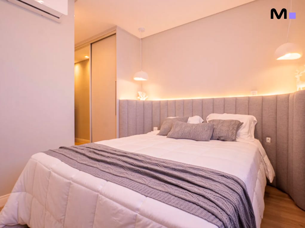 Quarto moderno e iluminado no Edifício Leblon Residence, com cama de casal e cabeceira estofada.