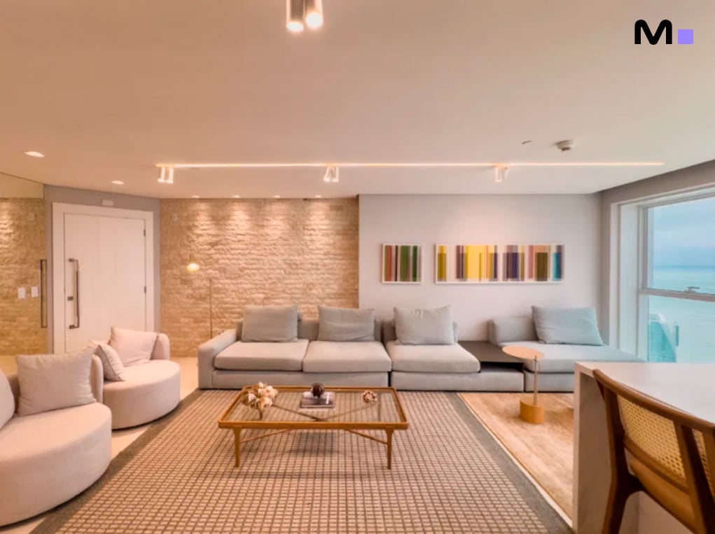 Sala de estar moderna e iluminada no Infinity Coast Residence com sofá modular e decoração minimalista.