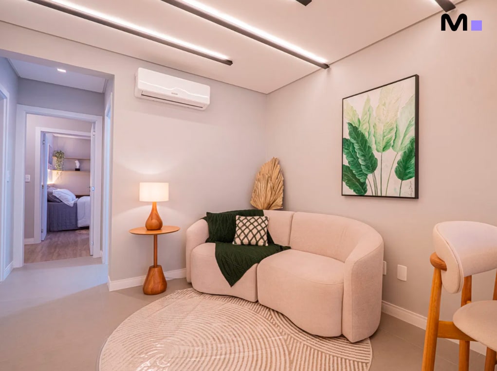 Sala de estar moderna com sofá curvo bege, tapete redondo e decoração minimalista. Edifício Leblon Residence.