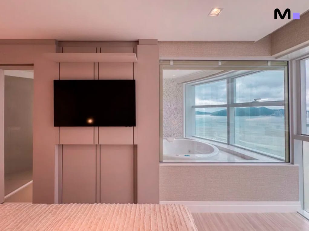 Quarto moderno com TV e banheira de hidromassagem com vista para o mar no Infinity Coast Residence.