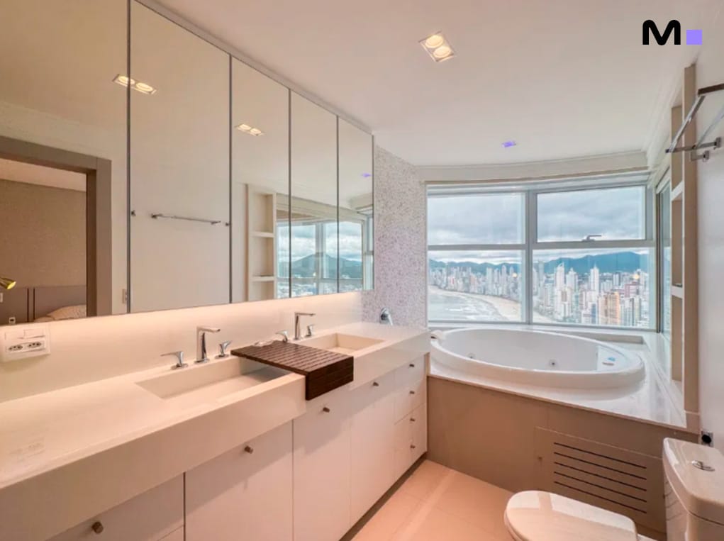 Banheiro moderno com vista para a cidade no Infinity Coast Residence. Banheira de hidromassagem e pia dupla.