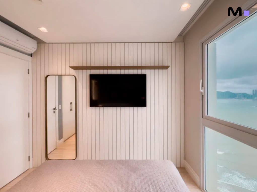 Quarto moderno com TV, espelho e vista para o mar no Infinity Coast Residence.