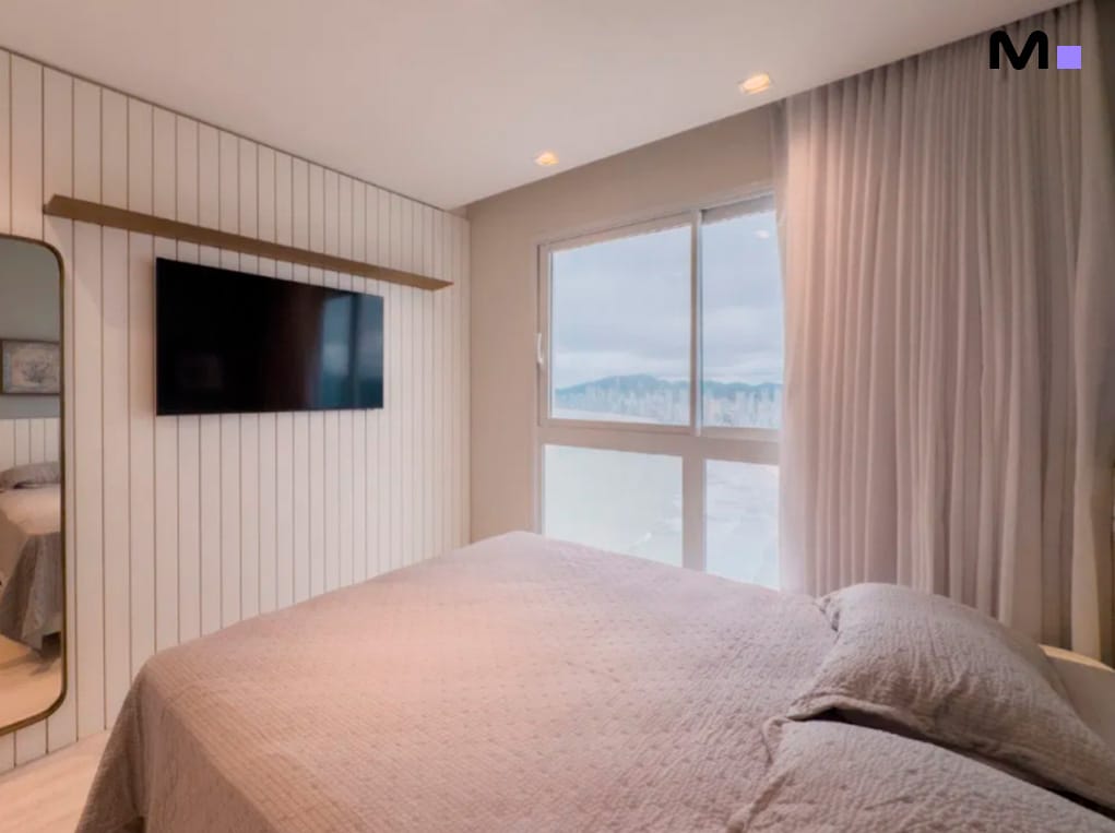 Quarto moderno no Infinity Coast Residence com cama de casal e vista da cidade.