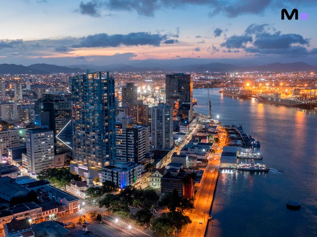 Vista noturna do centro da cidade com prédios altos e iluminação urbana. Down Town by Housi.