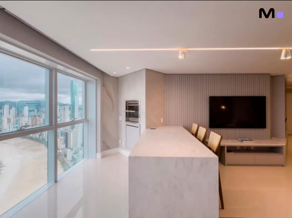 Interior moderno do Infinity Coast Residence com vista para a praia e cozinha integrada.