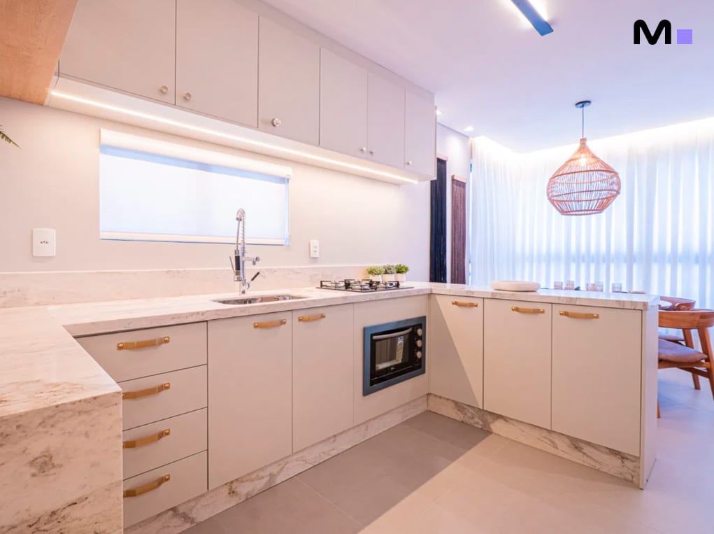 Cozinha moderna e luminosa no Edifício Leblon Residence. Armários claros e bancada de mármore.