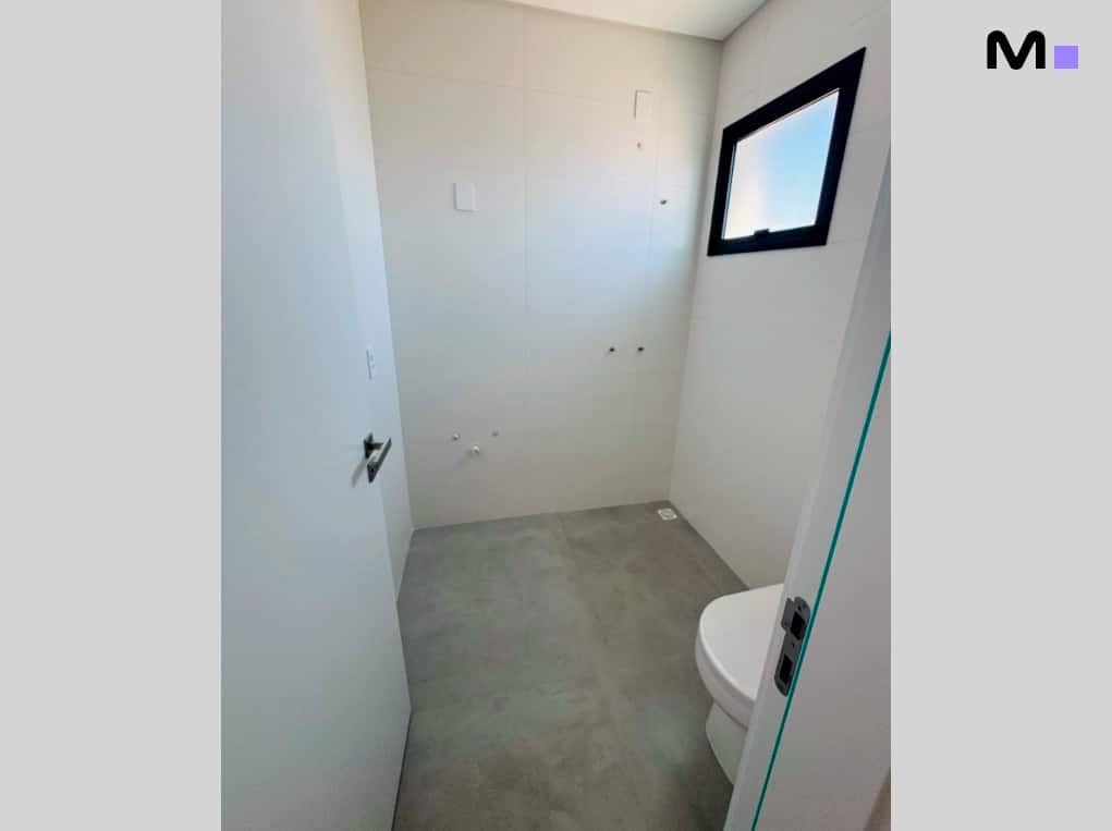 Banheiro moderno com vaso sanitário branco e azulejos claros.