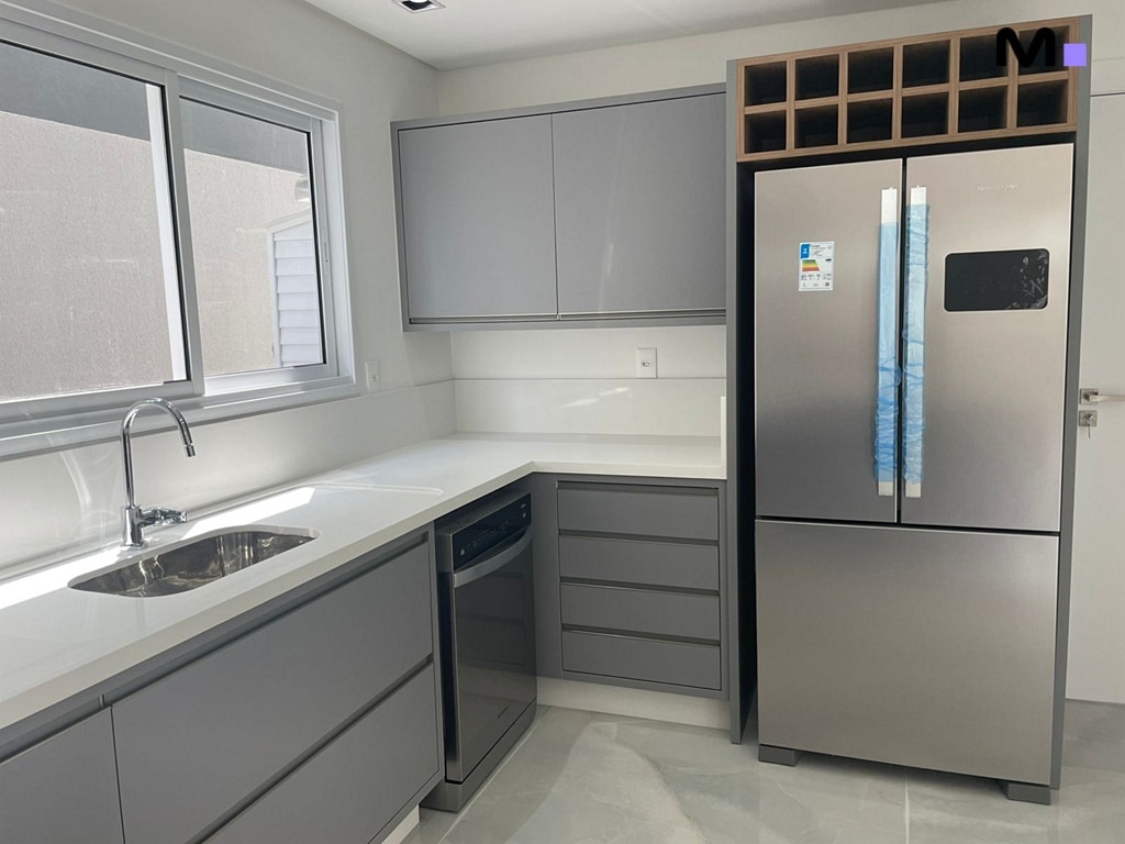 Cozinha moderna com pia, armários cinzas e geladeira inox no Condomínio House Haras.