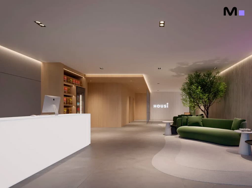 Recepção moderna da Housi Down Town com balcão branco e área de estar verde. "HOUSI" em destaque.