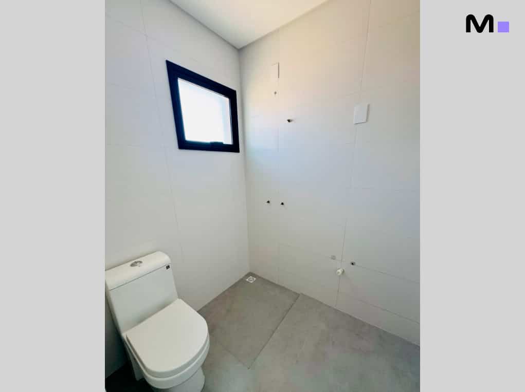 Banheiro moderno com vaso sanitário branco e janela preta. Edifício Ocean Cay.