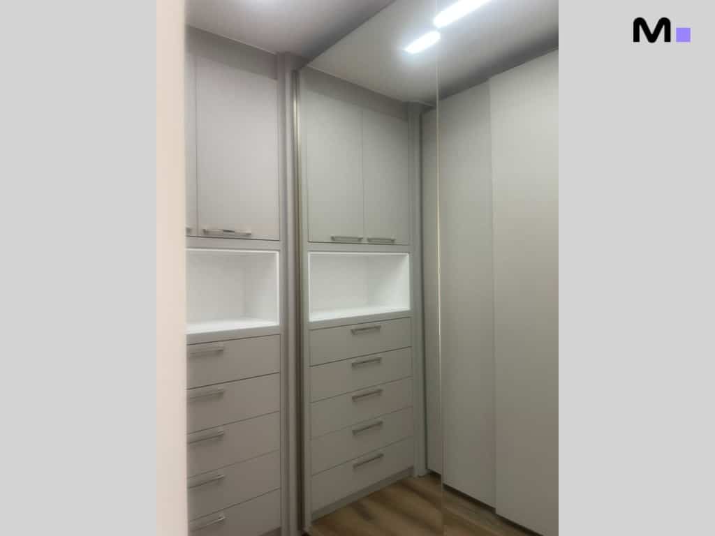 Armário embutido cinza com gavetas e prateleiras iluminadas. Design moderno e funcional.