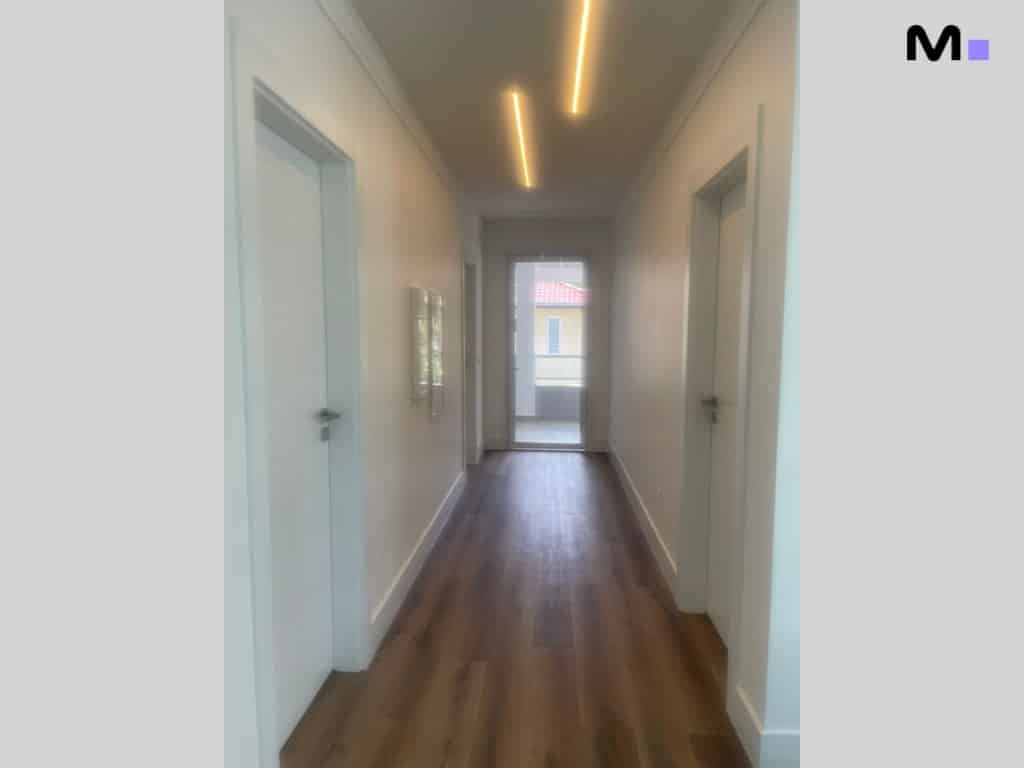 Corredor moderno com piso de madeira em condomínio House Haras.