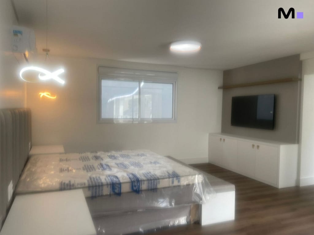 Quarto moderno com cama king size e TV em condomínio.