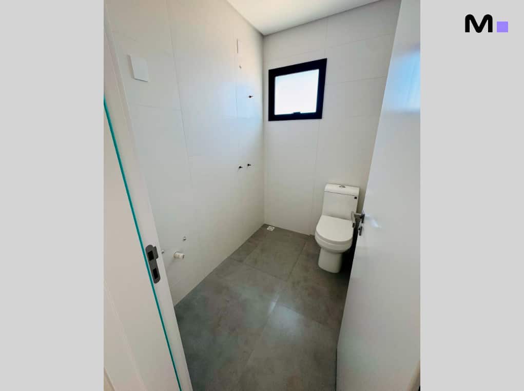 Banheiro moderno com vaso sanitário branco e janela quadrada no Edifício Ocean Cay.