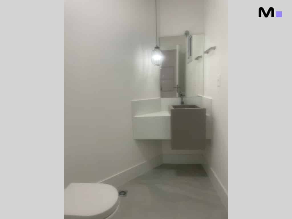 Banheiro moderno com pia suspensa e vaso sanitário branco.