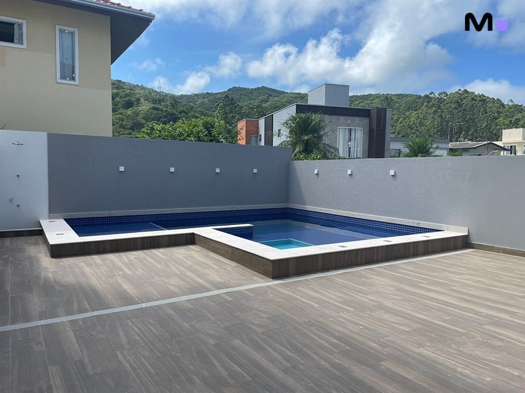 Piscina moderna em condomínio com deck de madeira e vista para montanhas.