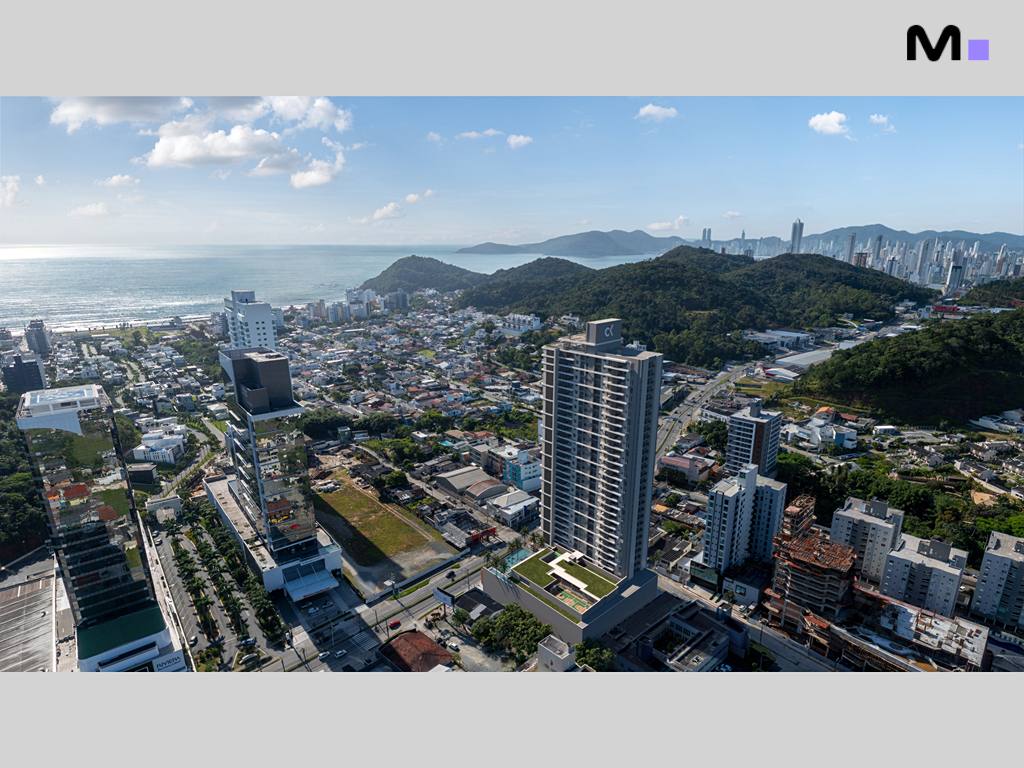 Vista aérea do Habitat Praia Brava, mostrando o prédio e a paisagem urbana com praia e montanhas.