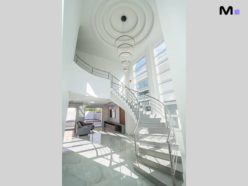 Hall de entrada moderno no Condomínio House Haras com escada e iluminação circular.