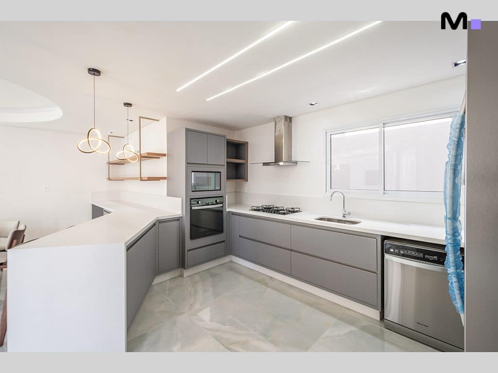 Cozinha moderna e elegante no Condomínio House Haras, com armários cinzas e bancada branca.