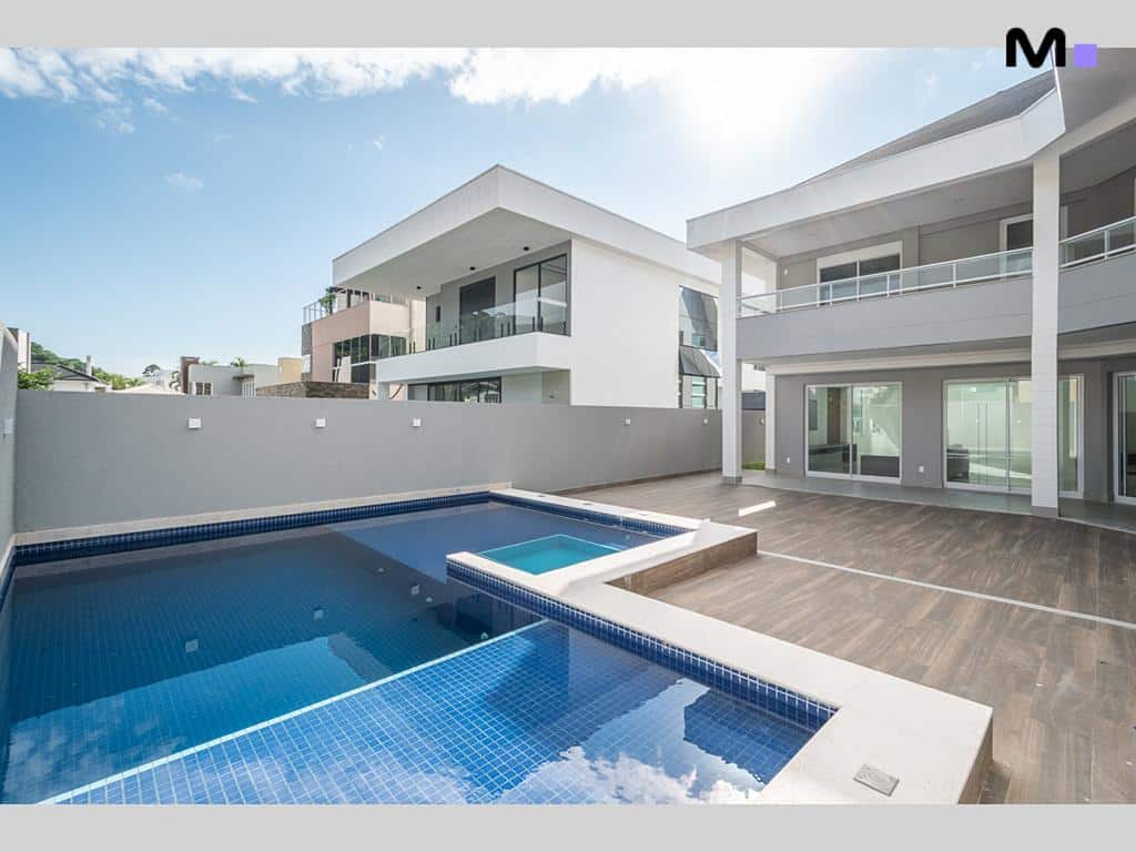 Piscina moderna em Condomínio House Haras, com casas de luxo ao fundo.