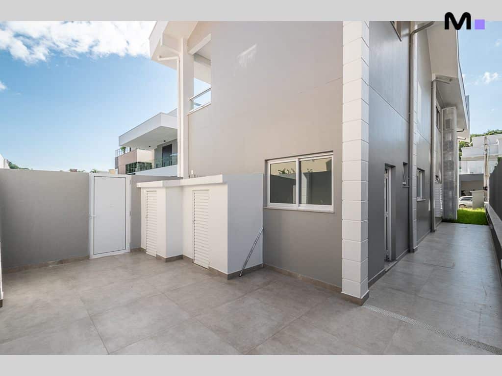 Área externa moderna do Condomínio House Haras com piso cinza e detalhes arquitetônicos brancos.