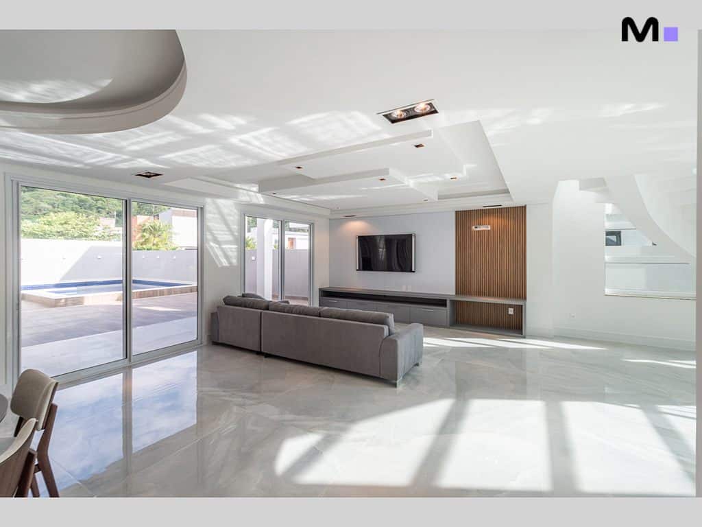 Sala de estar moderna e iluminada no Condomínio House Haras, com piso de mármore e vista para a piscina.