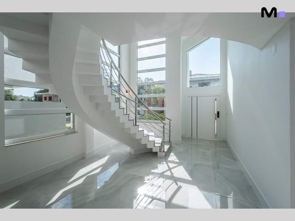 Escada espiral branca moderna em hall de entrada iluminado no Condomínio House Haras.