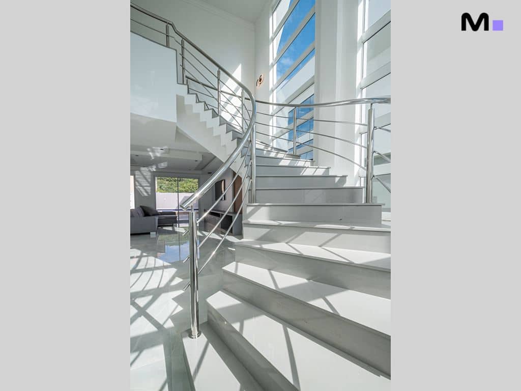Escada moderna de mármore branco com corrimão de metal no Condomínio House Haras.