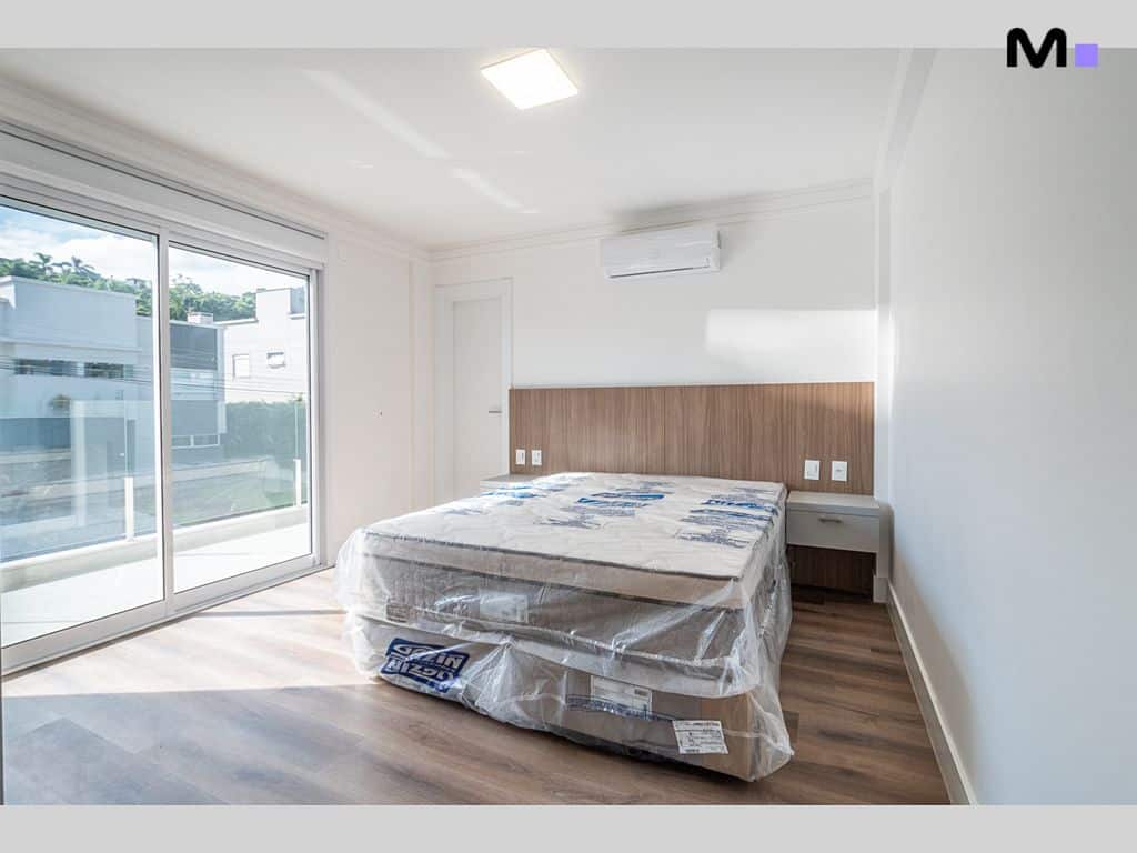 Quarto moderno com cama embalada no Condomínio House Haras. Janela ampla e piso de madeira.
