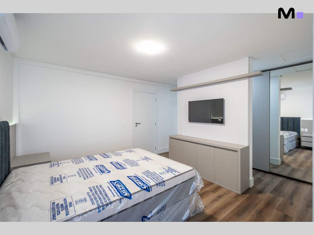 Quarto moderno com cama embalada no Condomínio House Haras. Design clean, TV e armário espelhado.