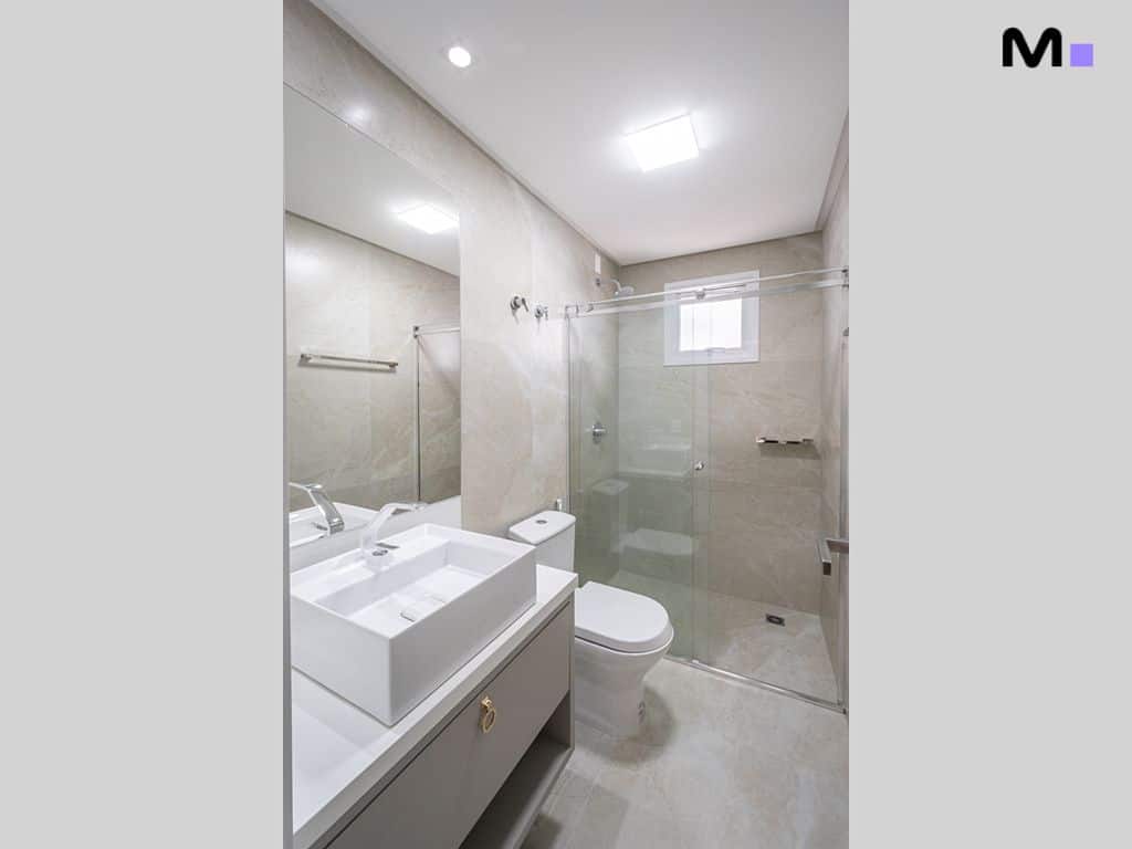Banheiro moderno e clean com pia retangular, vaso sanitário e box de vidro no Condomínio House Haras.