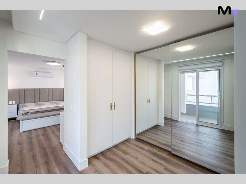 Quarto moderno com armário branco e espelho no Condomínio House Haras.