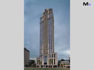 Edifício alto e moderno com detalhes arquitetônicos elegantes. Fachada clara e janelas simétricas.