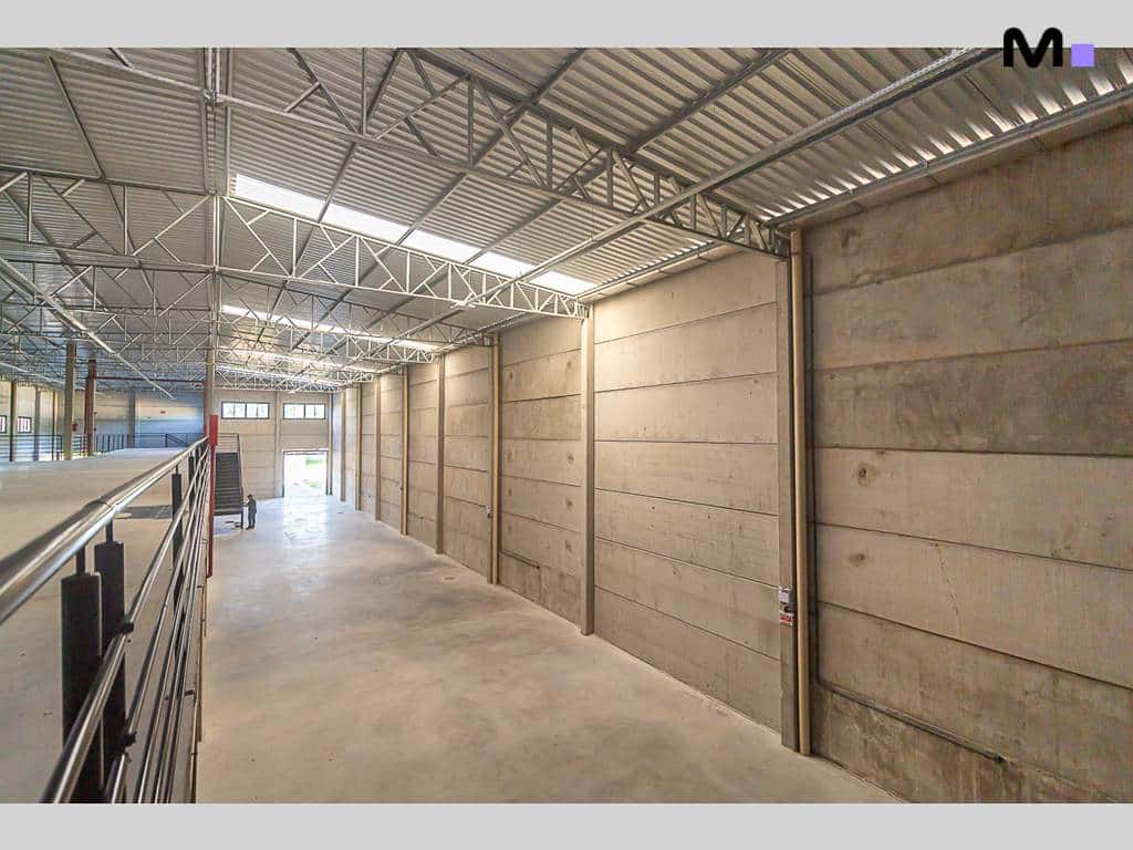 Interior do ABC Business Park: corredor iluminado com paredes de concreto e estrutura metálica no teto.