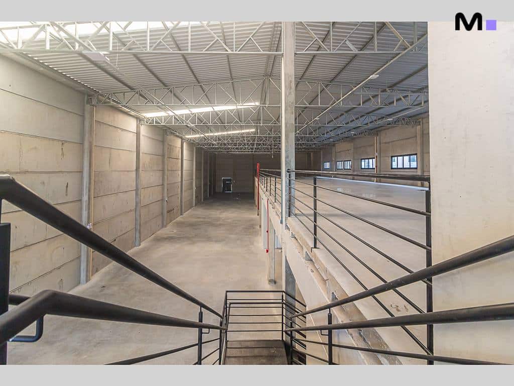Interior de armazém no ABC Business Park com estrutura metálica e paredes de concreto.