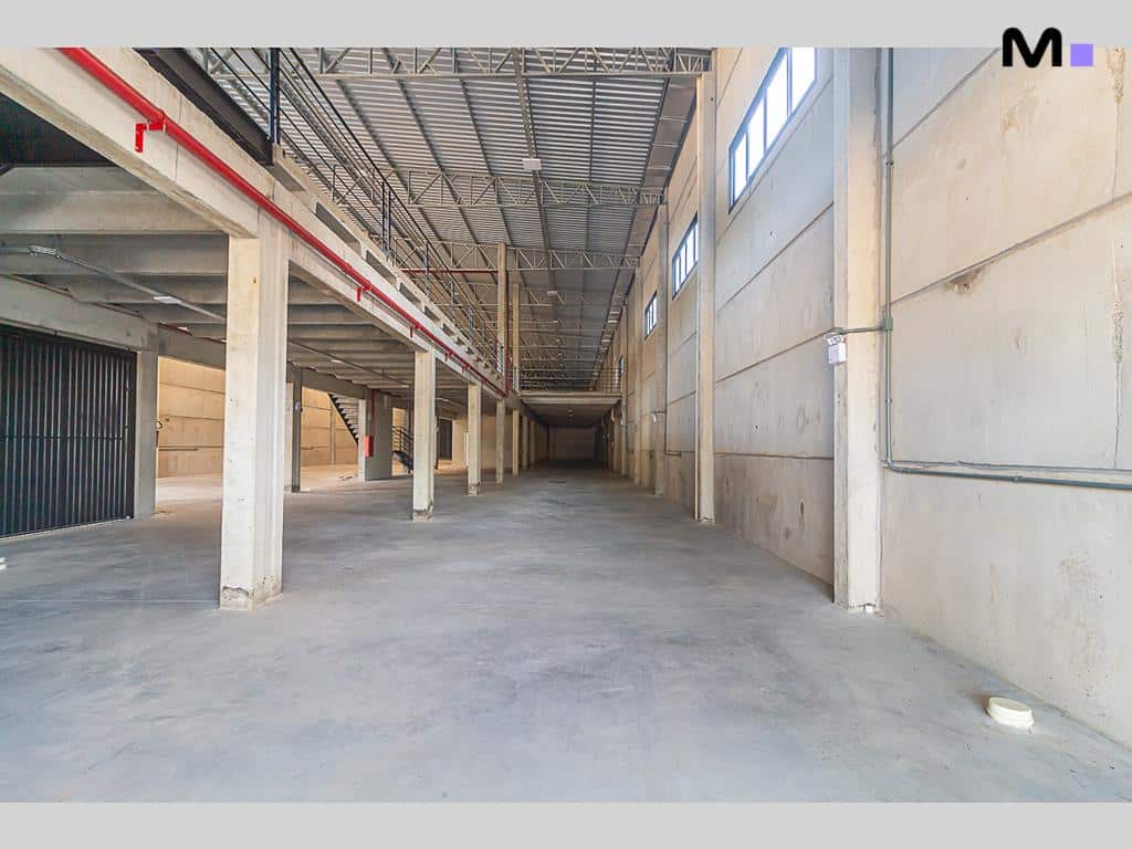 Interior amplo de armazém no ABC Business Park com colunas de concreto e teto metálico.