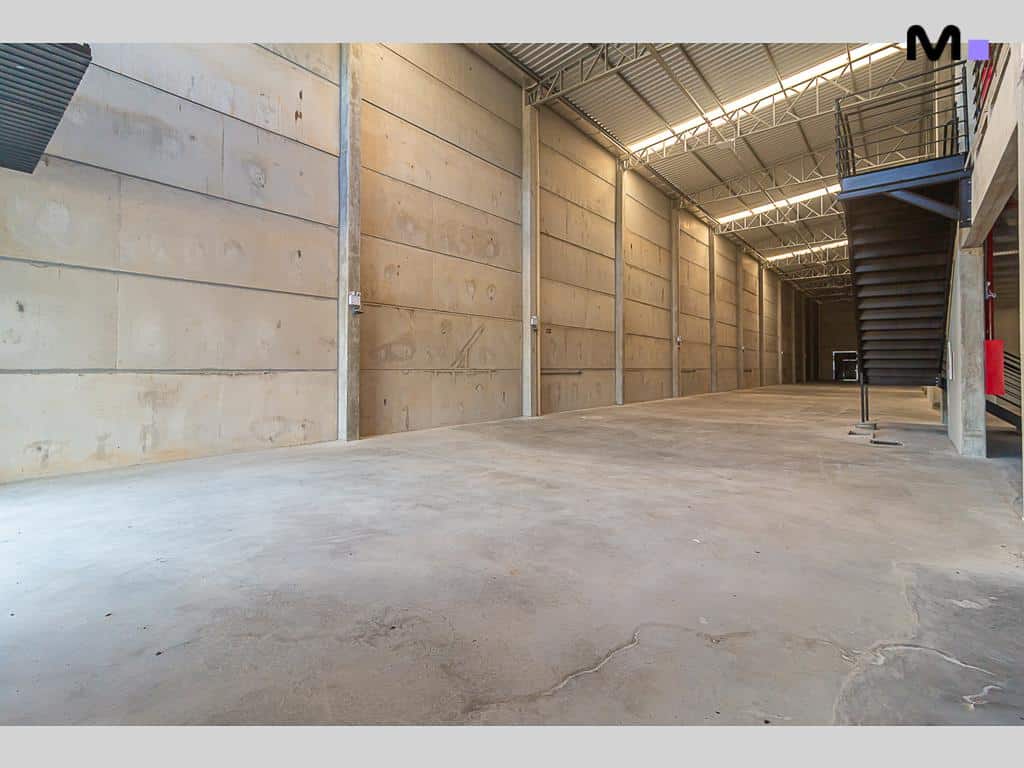 Interior espaçoso de galpão no ABC Business Park. Paredes de concreto e estrutura metálica do teto.