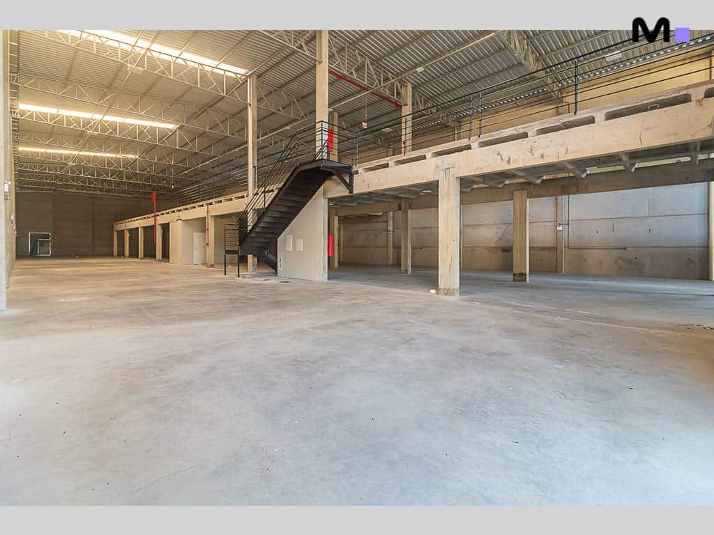 Interior espaçoso de armazém no ABC Business Park, com mezanino e estrutura metálica.