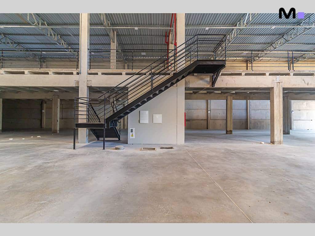 Interior do ABC Business Park com escadas pretas e estrutura de concreto. Espaço amplo e industrial.